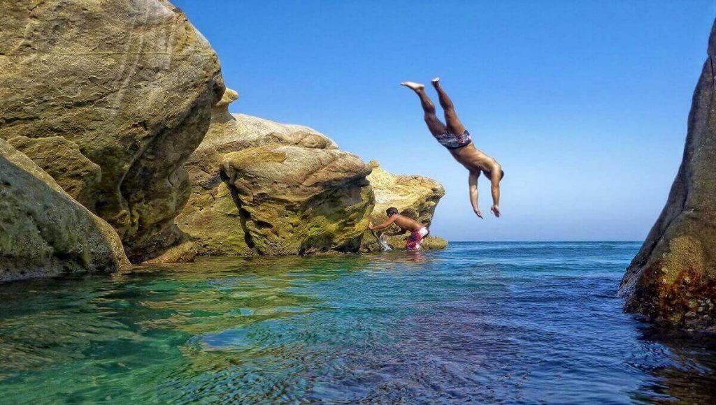 Man jumps into the crystal clear water at Manilva's rocky beach